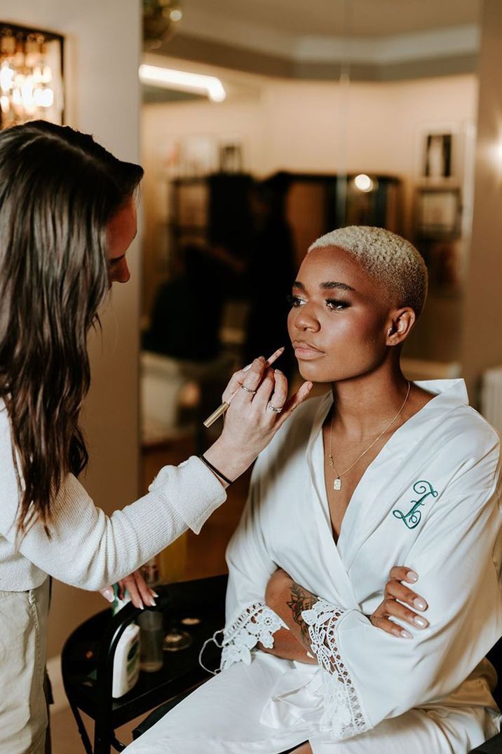 bride-in-white-robe-getting-makeup-done-for-wedding-day