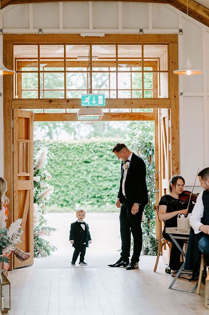 toddler and man wearing a tux, about to walk down the aisle for wedding with black tie dress code