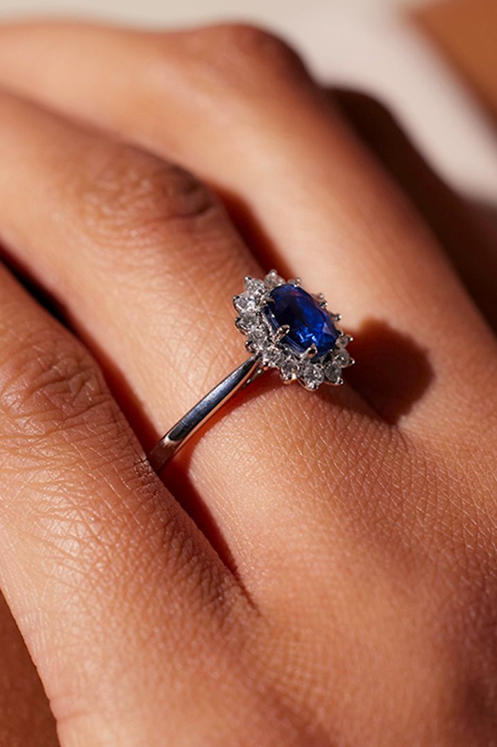 blue-sapphire-oval-diamond-halo-engagement-ring-on-hand