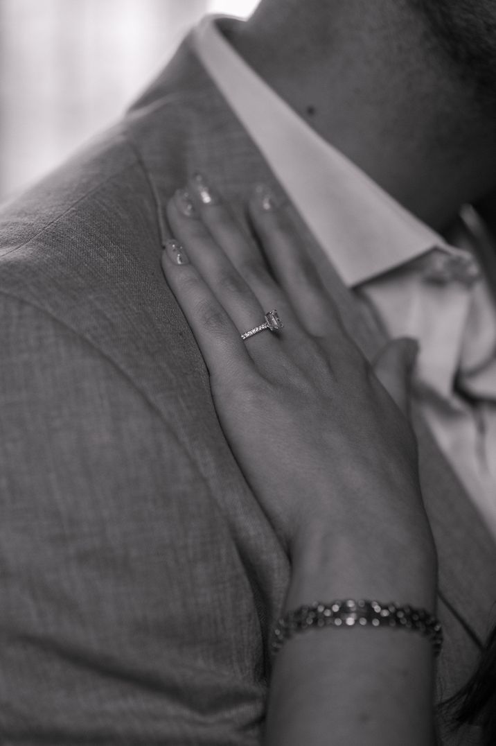 diamond-engagement-ring-on-hand-resting-on-suit-lapel.