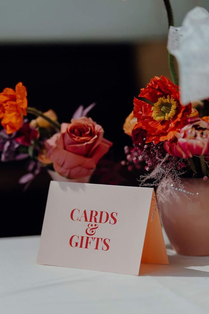 card-and-gifts-wedding-sign-surrounded-by-pink-flowers