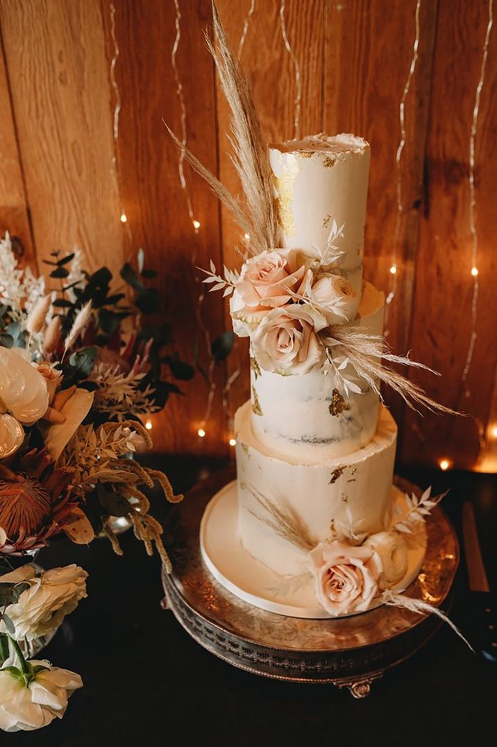 Rustic three tier wedding cake decorated with pink roses and pampas grass