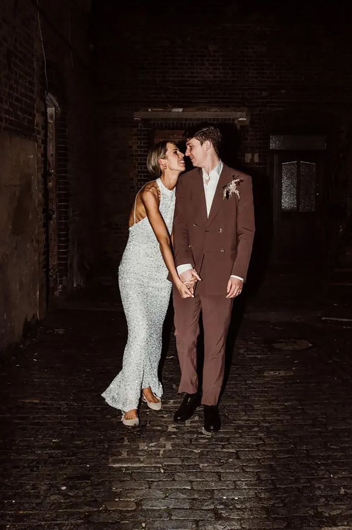 Bride in sparkly evening wedding dress with groom in brown wedding suit