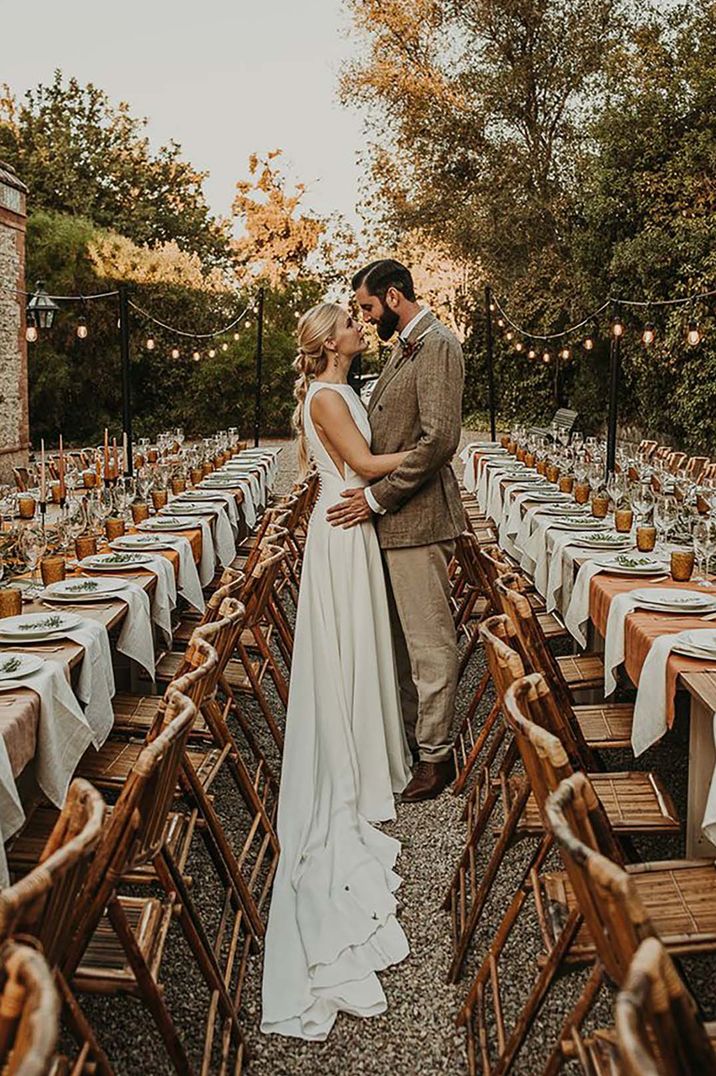 bride and groom embracing at outdoor wedding with earthy toned table decor