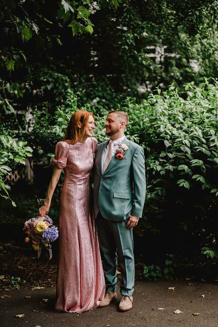 bride wearing pink metallic wedding dress and groom in green suit