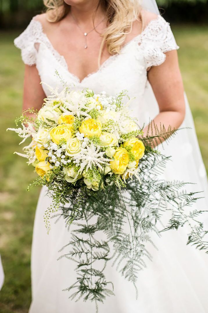 bride holding a wedding bouquet with bright yellow flowers