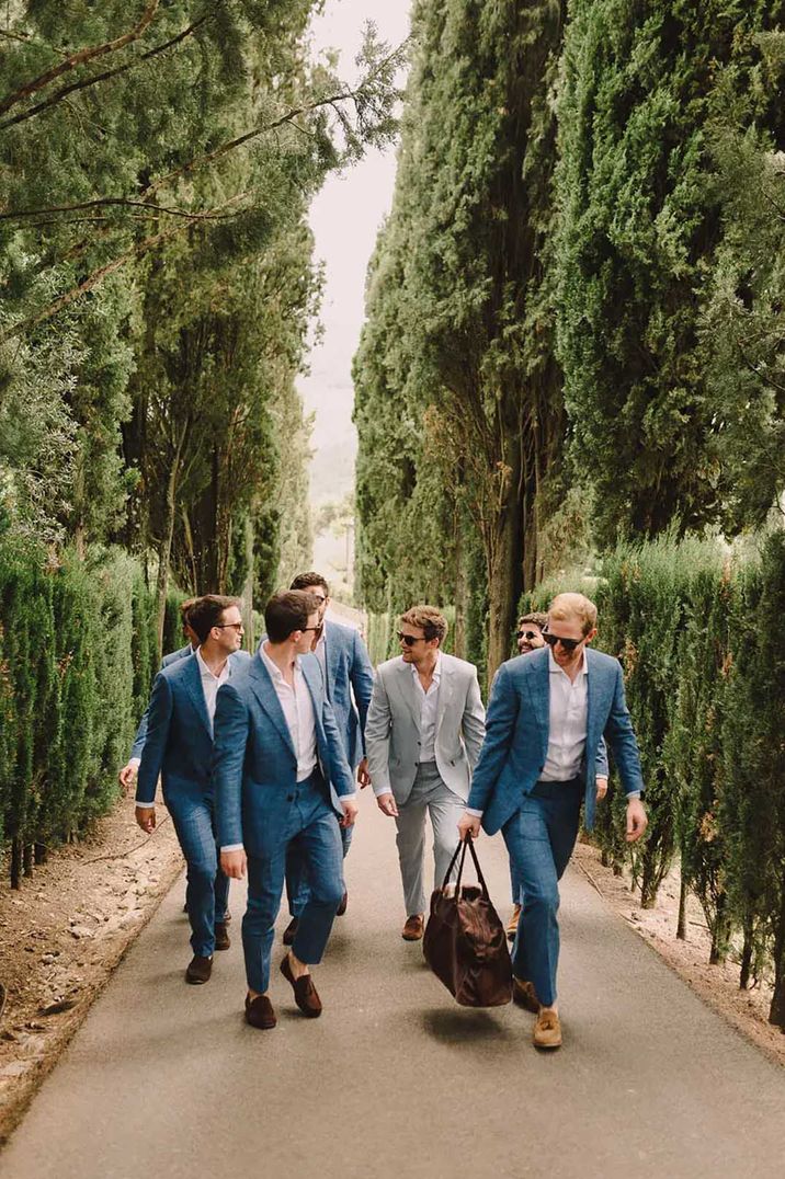 groomsmen wearing blue suits and groom wearing light grey wedding suit