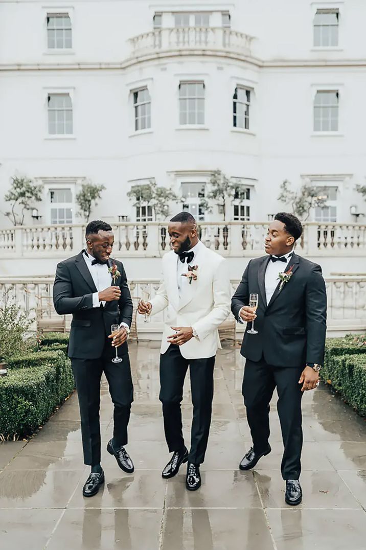 groomsmen wearing black tuxedos and groom wearing white tuxedo