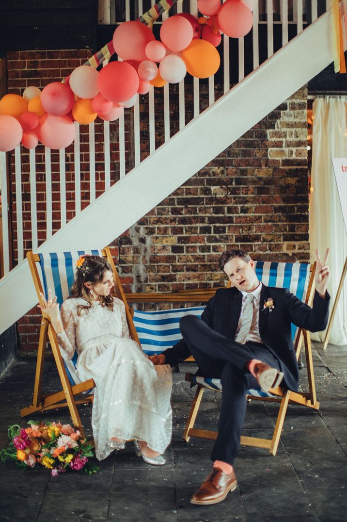 Bride and Groom Sitting on Deck Chairs with Balloon Arch Lining the Stairs