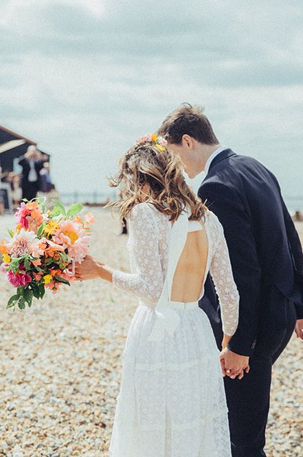 Backless lace wedding dress with coral bridal bouquet