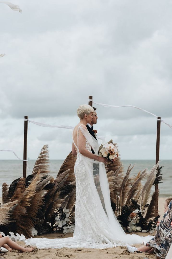 Bride and groom standing at the altar with dried grass floral arrangement