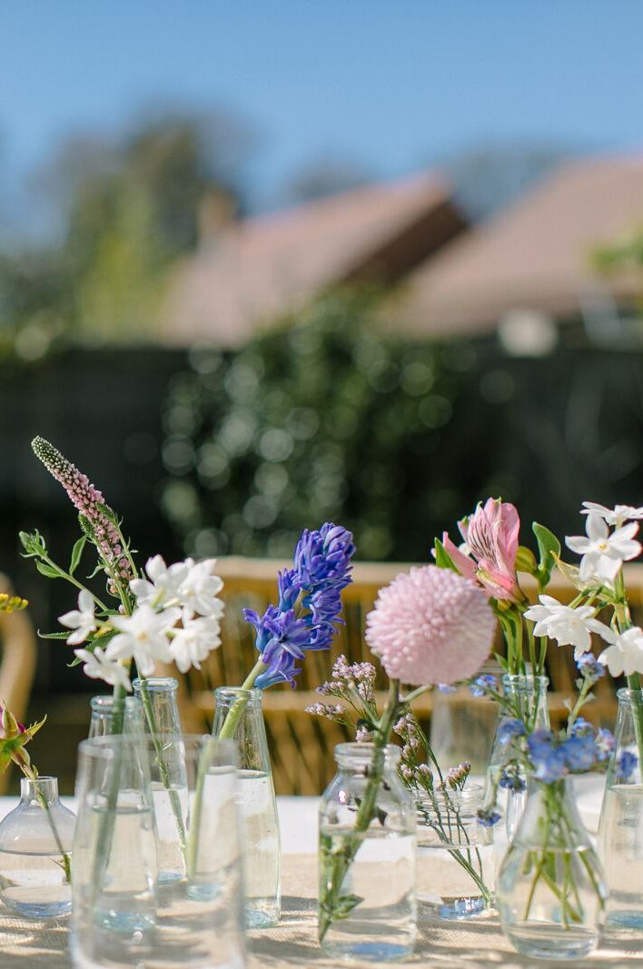 Wedding centrepiece for an outdoor garden wedding using single stems of spring flowers