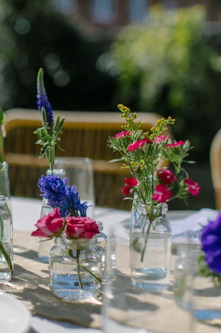 Wedding centrepiece created using single stems of roses, hyacinth and forget-me-nots in mini glass vases