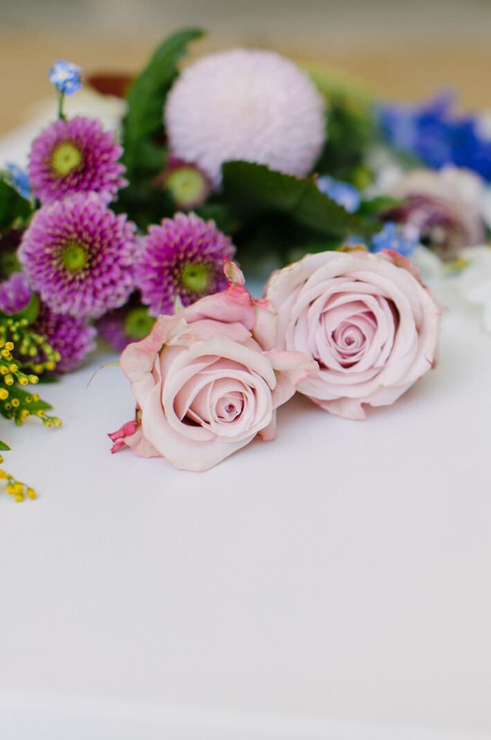 Freshly cut roses, wax flowers and mini chrysanthemums laid next to an assortment of clear glass vessels