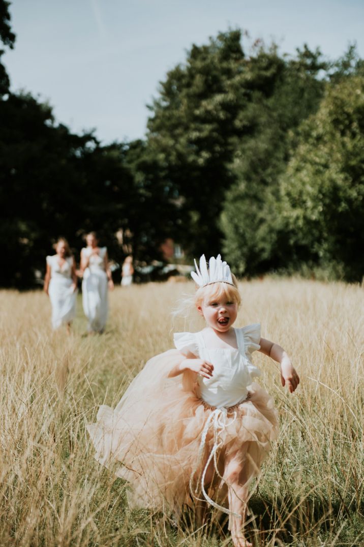 Little flower girl in peach tulle skirt and feather headdress