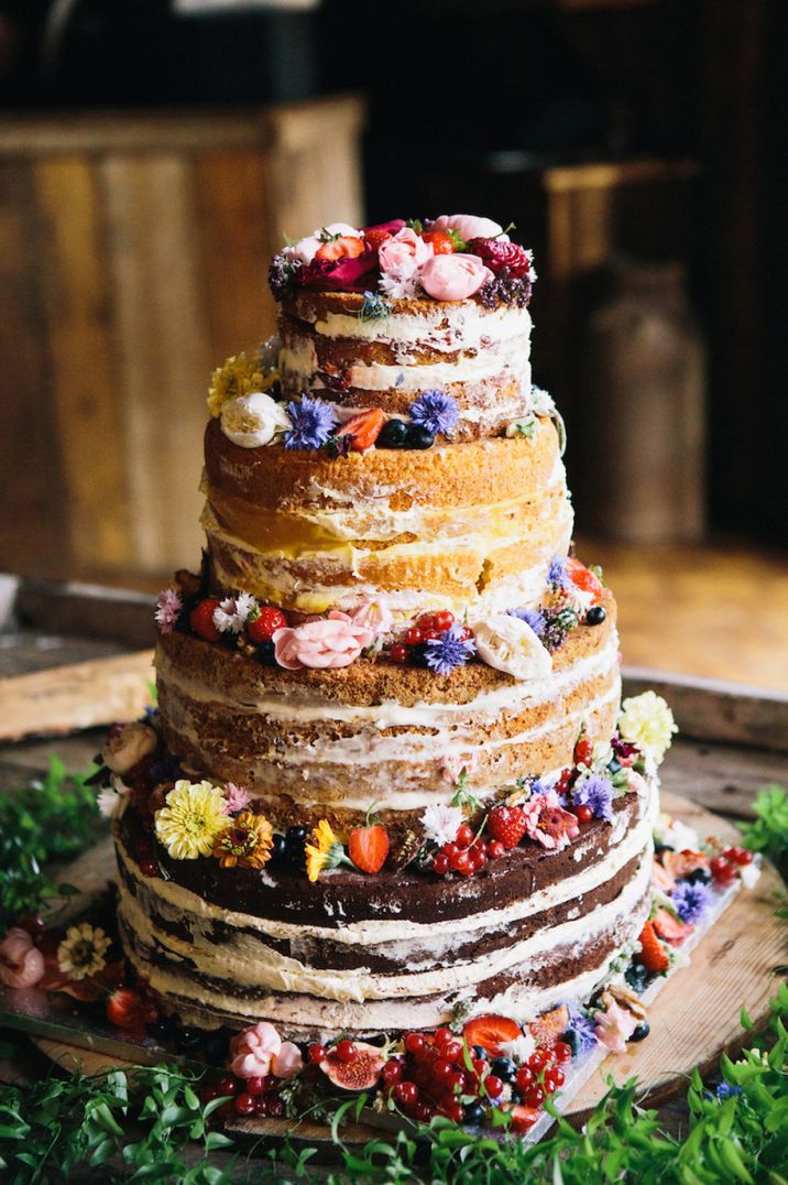 Mixed four tier naked wedding cake with flowers between layers