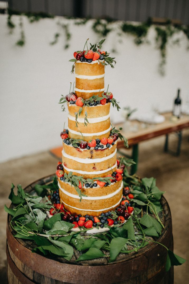 Four tier naked wedding cake with berries and green foliage