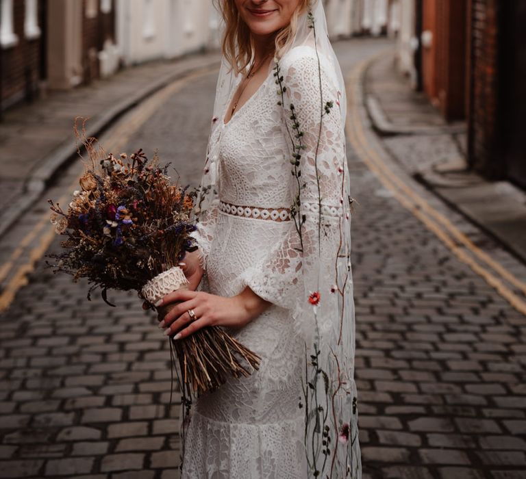 Boho bride with lace wedding dress, flower crown and embroidered veil 