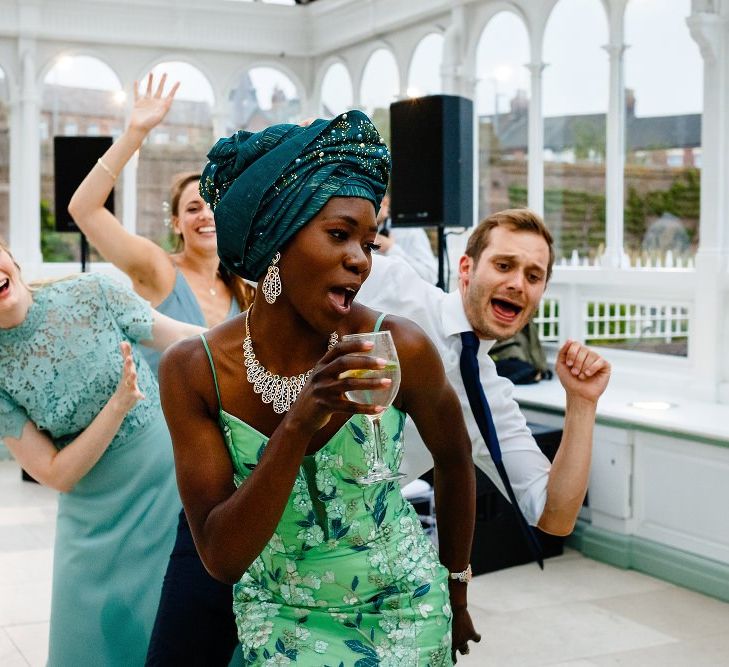 Bride in green Nigerian outfit dancing during the money dance 