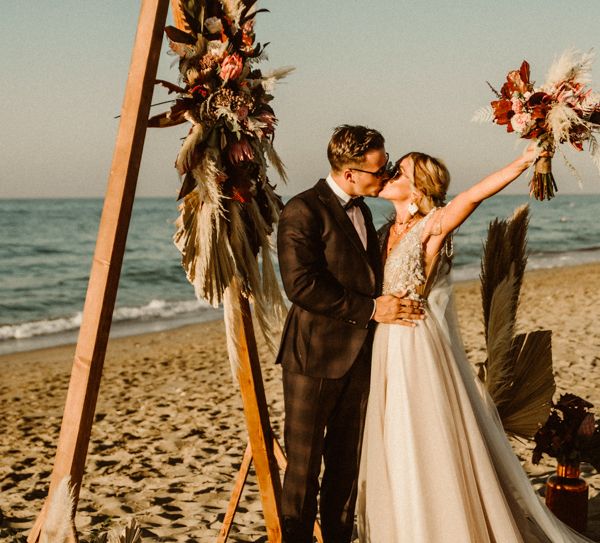 Bride and groom kiss after wedding ceremony and the bride olds her bouquet in the air