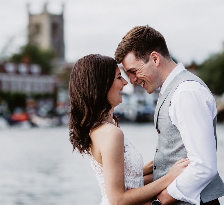 Bride & groom embrace on wedding day with river background