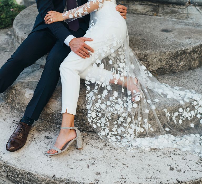 Bride in wedding jumpsuit with appliqué train and silver shoes