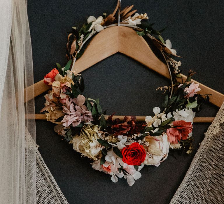 Wedding dress hanging on door with red dried floral crown