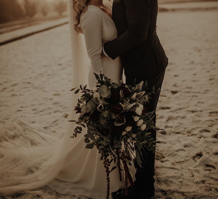 Bride clutches foliage bouquet at Eaves Hall wedding