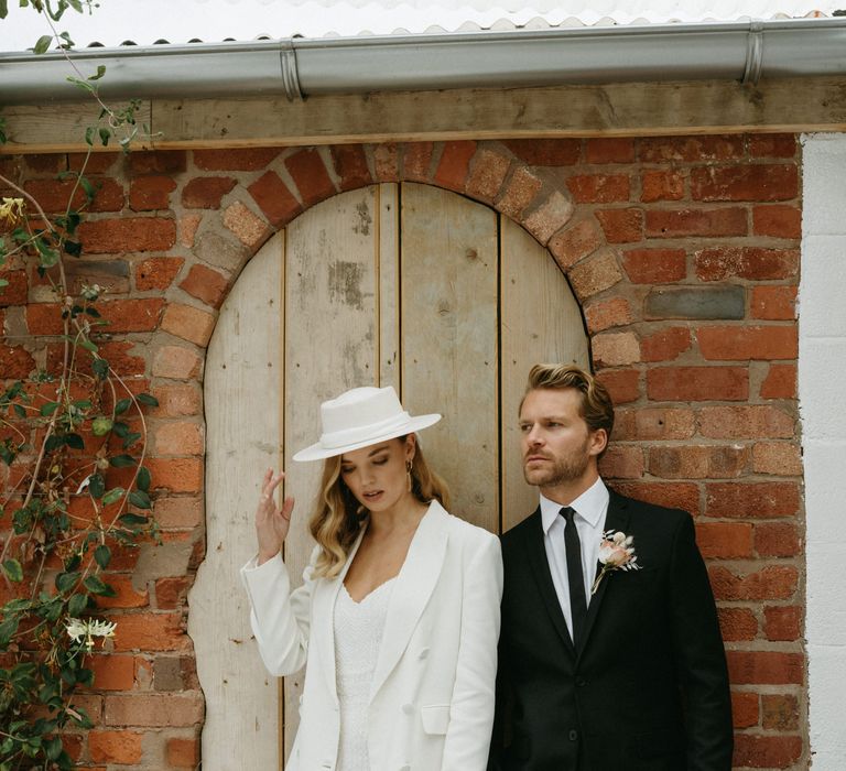 Stylish bride in a sequin jumpsuit, white blazer and bridal hat