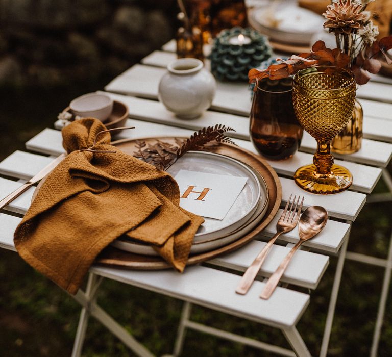 Rustic table decor with orange napkins and small floral bouquets