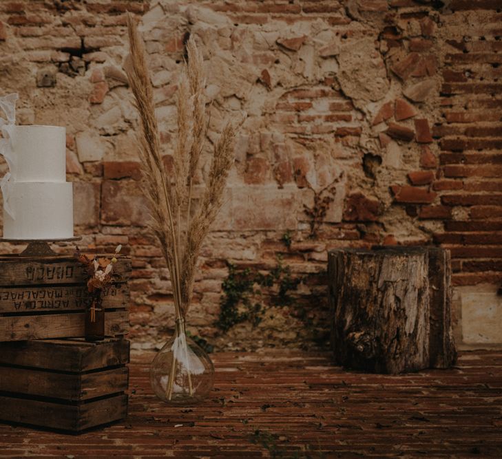 Cake display on wooden crates with apothecary jar filled with pampas grass 