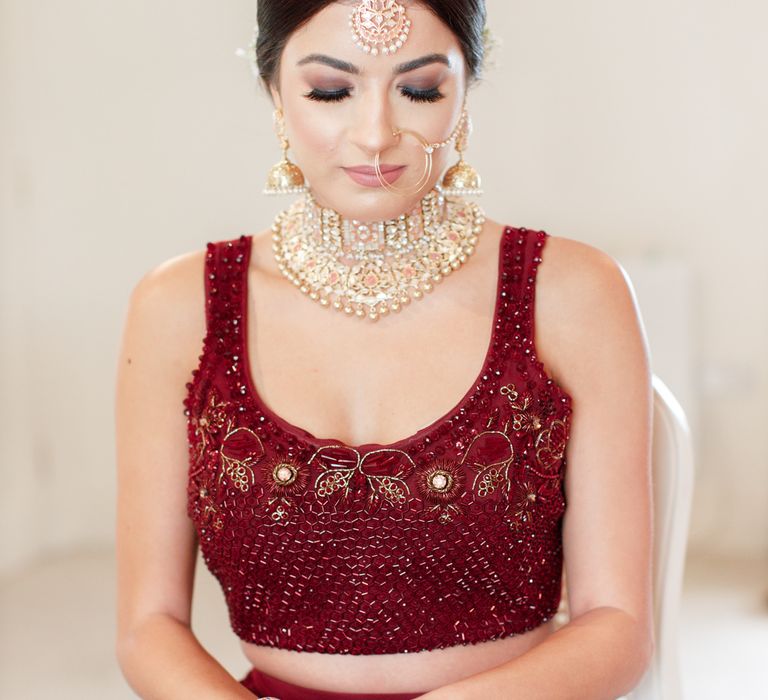 Bride wears gold jewellery and burgundy outfit