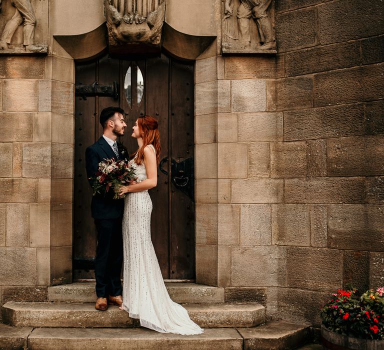 Bride & groom stand in front of Manor house after wedding ceremony