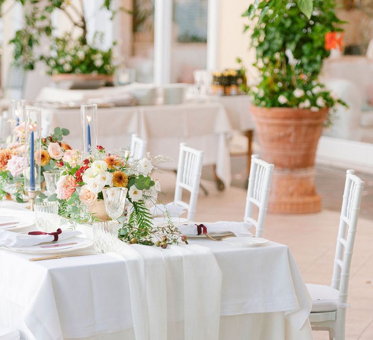 White banquet table for an outdoor Italian wedding with autumnal floral centrepieces