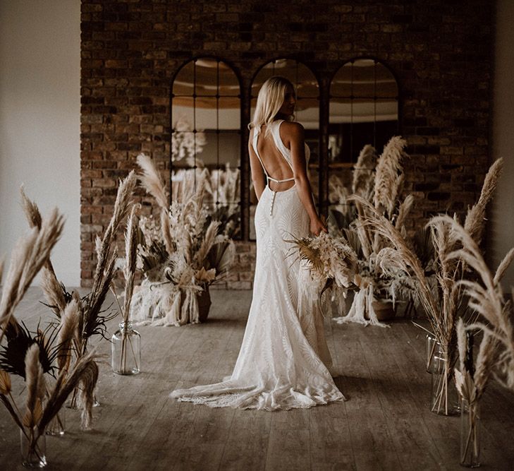 Bride in a patterned backless wedding dress standing in the dried flower aisle at Pryors Hayes wedding venue 