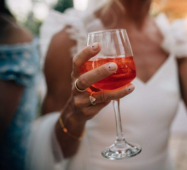 Bride holding an Aperol Spritz with minimal wedding nail design