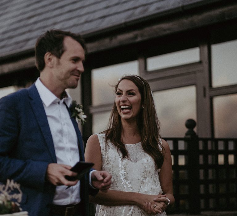 Bride & groom laugh together outdoors on their wedding day