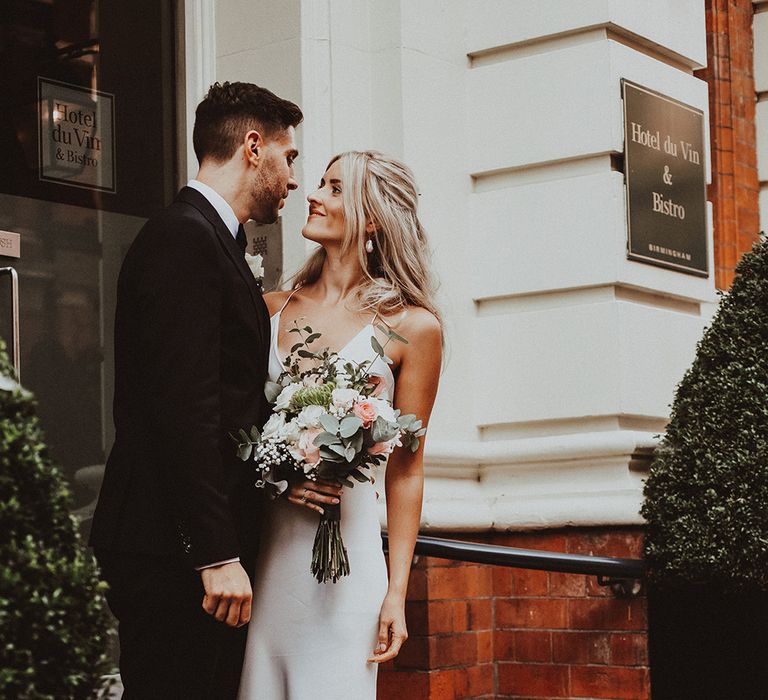 Bride and groom portrait in a doorway in Birmingham with groom in a tuxedo and bride in a slip wedding dress with puddle train 