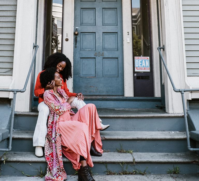 Brides-to-be sitting in a doorway during their engagement photoshoot 