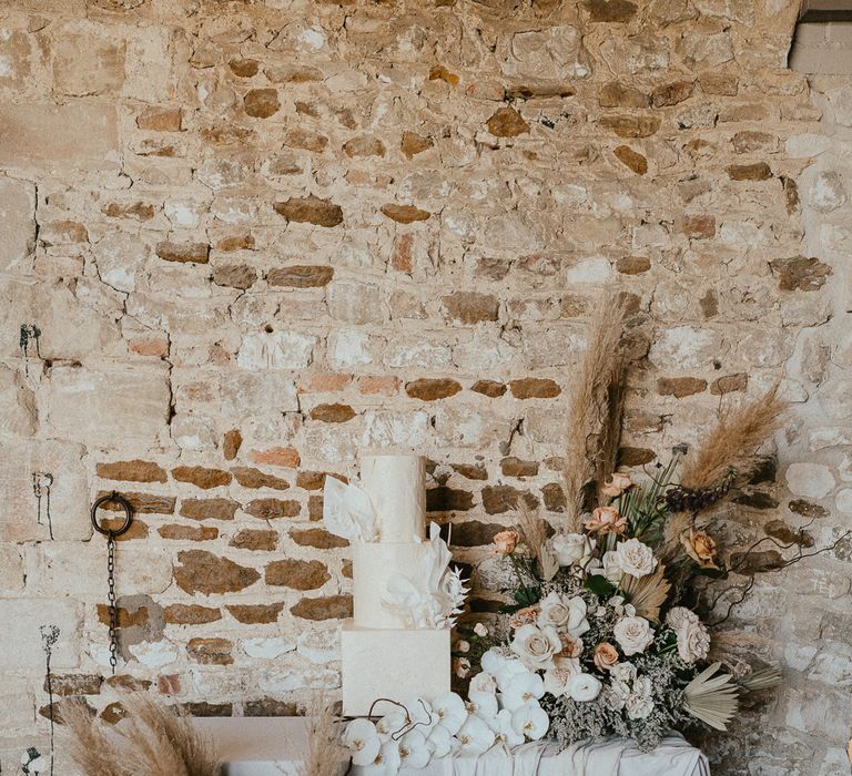 Wedding cake table with buttercream wedding cake and dried and fresh flower arrangements including roses, pampas grass and orchids 