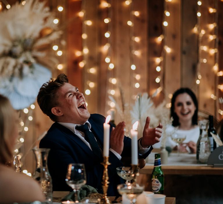 Wedding guest laughing at intimate 30 person wedding reception with fairy lights 