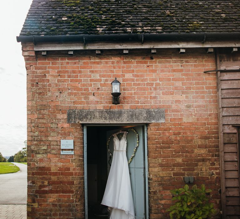 Brides gown hands outside rustic building in doorway