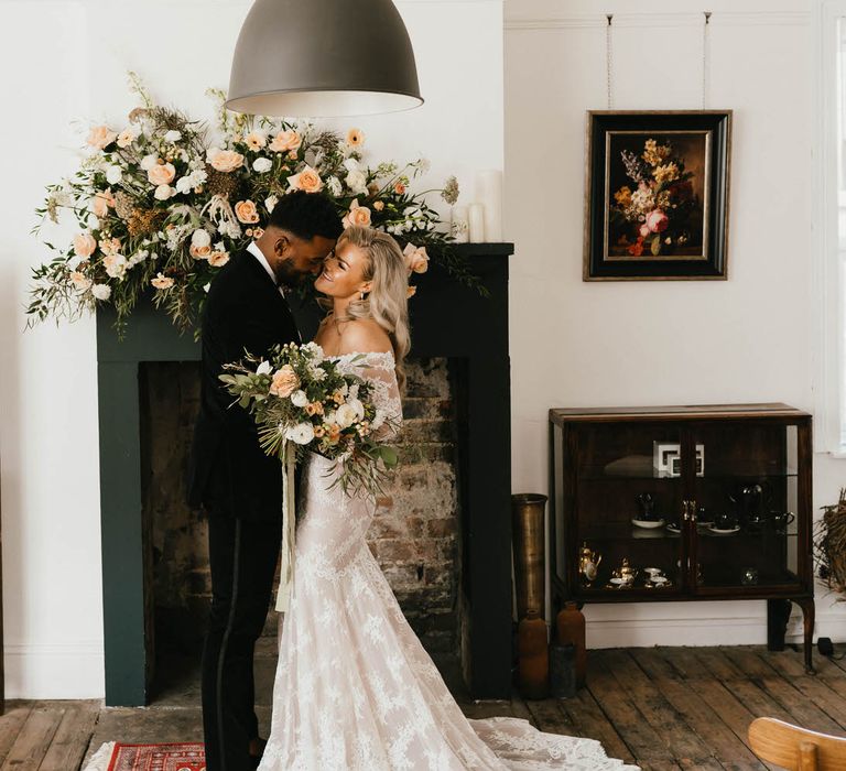 Bride and groom hugging and smiling at minimal micro wedding ceremony. The bride is wearing an off the shoulder lace wedding dress, with flowing blonde wavy hair