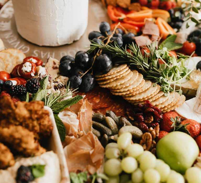 Small white wedding cake with abundant charcuterie board grazing table