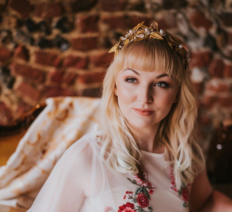 Blonde bride wearing gold flower hair accessory with red embroidered floral wedding dress for pumpkin spice wedding