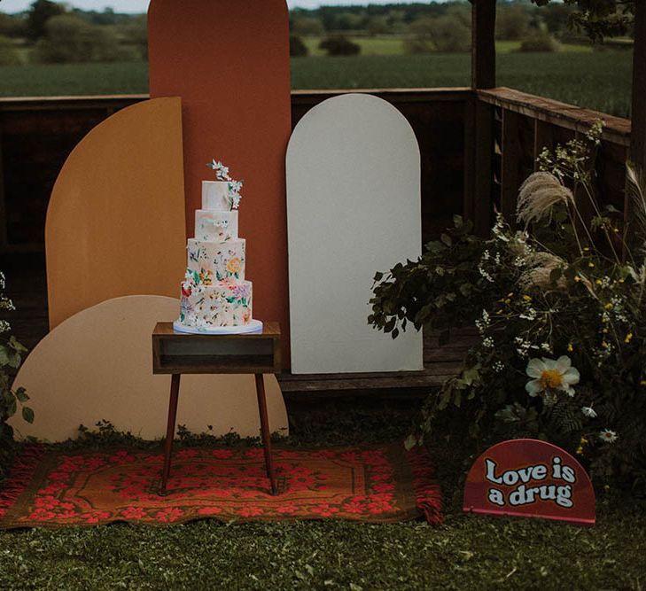 Geometric frame altar with wool rug, wild flowers and illustration wedding cake 