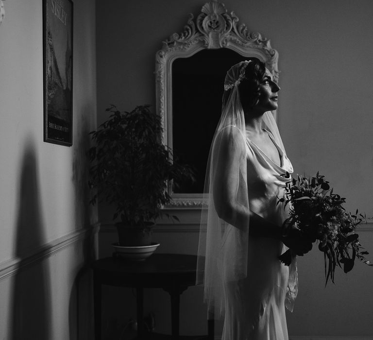 Beautiful black and white portrait of a bride in a satin wedding dress and Juliet wedding veil 