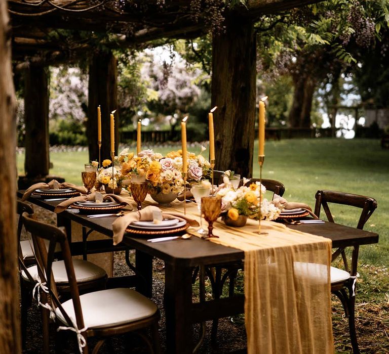 Intimate outdoor wedding reception under a pergola with honey yellow wedding decor and details 