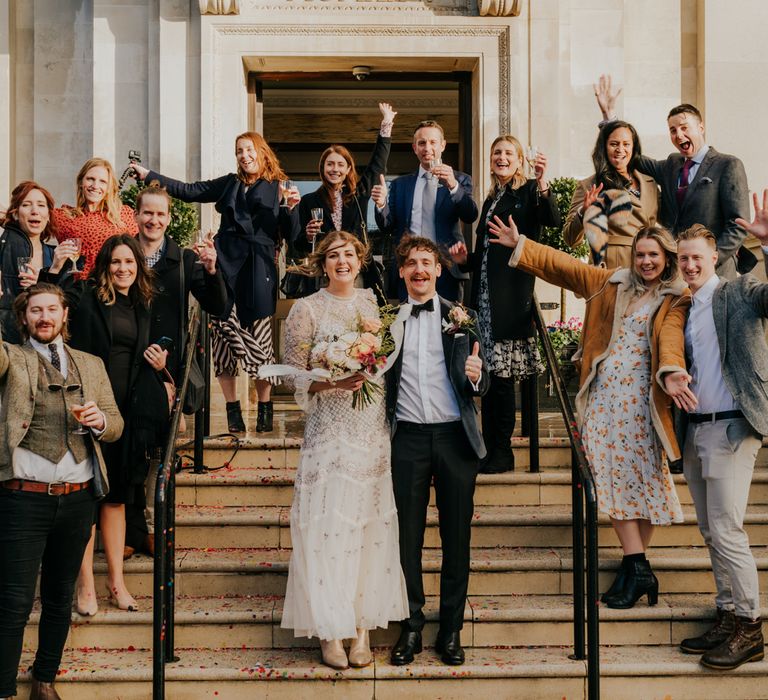 Bride & groom stand with their wedding party on Town Hall steps after wedding ceremony