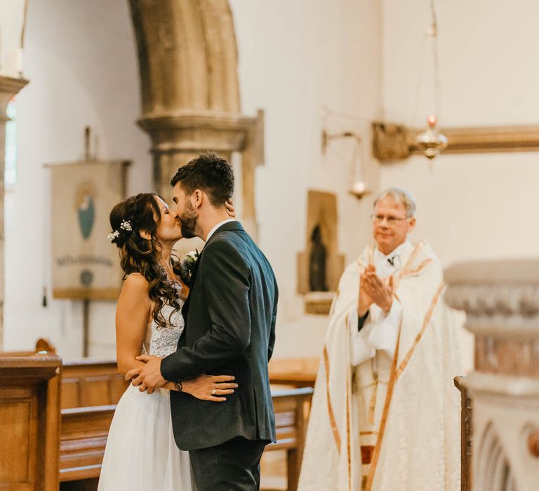 Bride & groom kiss on their wedding day during church ceremony